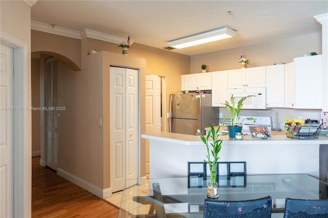 4704 SW 160th Ave Unit 216, Miramar, FL 33027 - kitchen with white microwave, freestanding refrigerator, arched walkways, white cabinetry, and crown molding