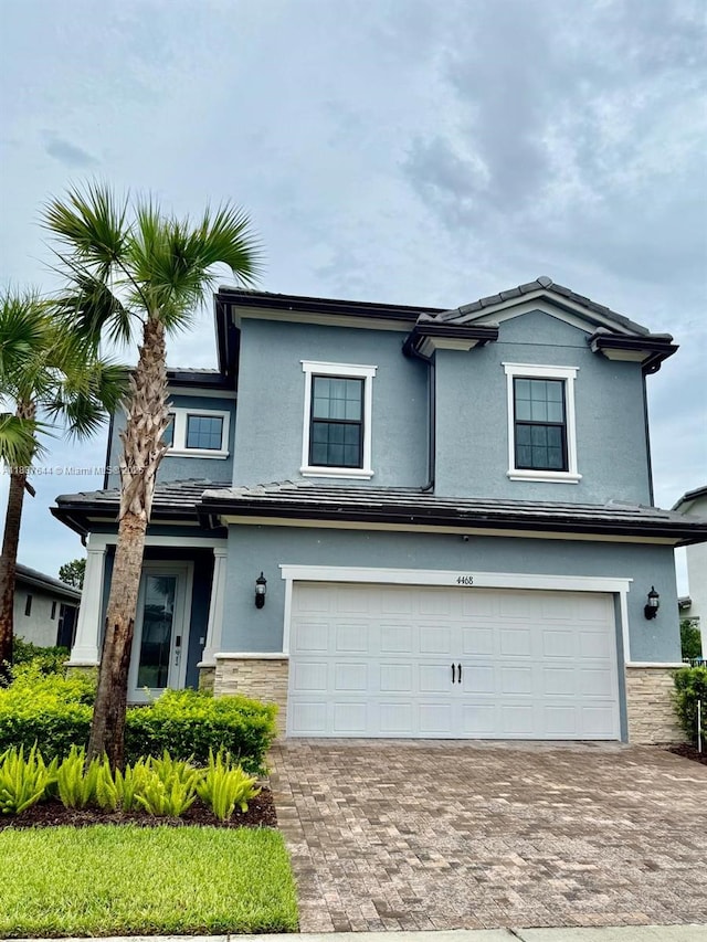 4468 Spruce Ln, Oakland Park, FL 33309 - view of front facade featuring an attached garage, stone siding, decorative driveway, and stucco siding