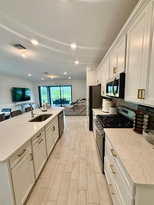 4468 Spruce Ln, Oakland Park, FL 33309 - kitchen featuring appliances with stainless steel finishes, open floor plan, light wood-style floors, backsplash, and light stone counters