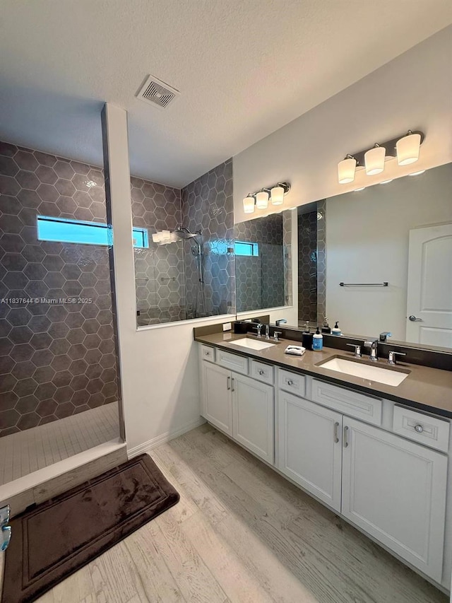 4468 Spruce Ln, Oakland Park, FL 33309 - full bathroom with double vanity, walk in shower, wood finished floors, and a textured ceiling