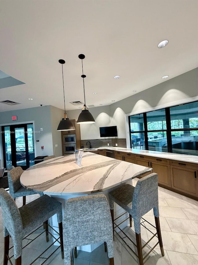 4468 Spruce Ln, Oakland Park, FL 33309 - kitchen with appliances with stainless steel finishes, hanging light fixtures, open floor plan, light stone countertops, and a large island with sink