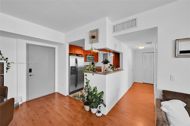 36 NW 6th Ave Unit 701, Miami, FL 33128 - kitchen featuring stainless steel appliances, light wood finished floors, and brown cabinetry