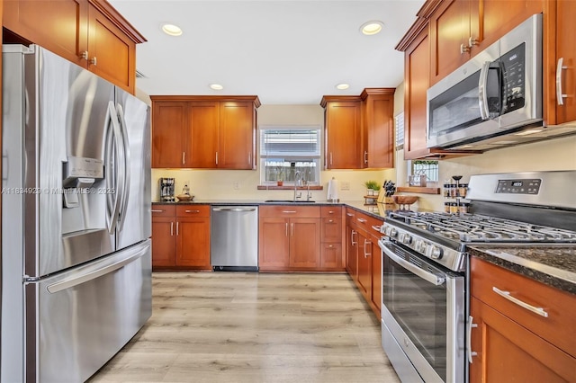 1533 Shenandoah St, Hollywood, FL 33020 - kitchen with stainless steel appliances, recessed lighting, light wood-style flooring, dark stone counters, and brown cabinets
