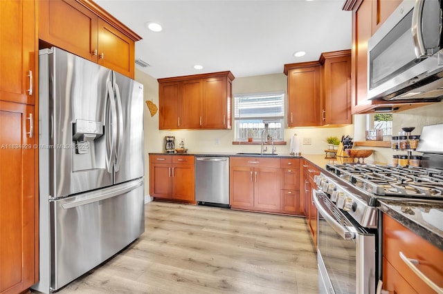 1533 Shenandoah St, Hollywood, FL 33020 - kitchen featuring stainless steel appliances, recessed lighting, light wood finished floors, brown cabinetry, and dark stone counters
