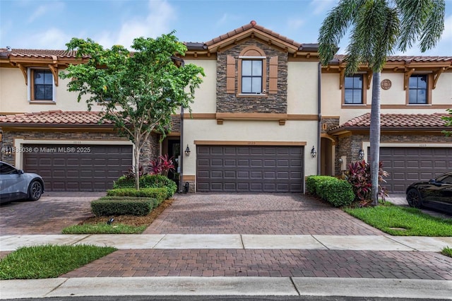 12125 S Vaquero Trails Dr, Davie, FL 33325 - townhome / multi-family property featuring stucco siding, a garage, decorative driveway, stone siding, and a tiled roof