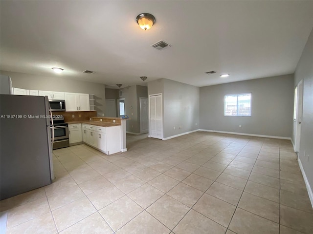 6124 SW 39th St, Miramar, FL 33023 - kitchen with appliances with stainless steel finishes, a peninsula, light tile patterned floors, open floor plan, and white cabinets