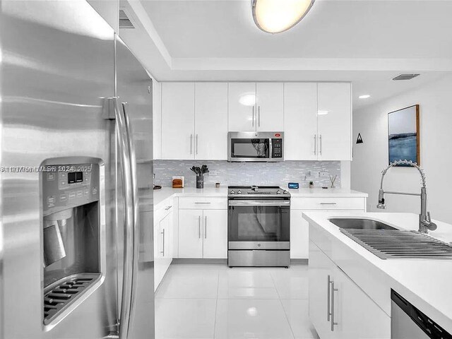 2651 NE 212th Ter Unit 202, Aventura, FL 33180 - kitchen with appliances with stainless steel finishes, light countertops, white cabinets, and decorative backsplash