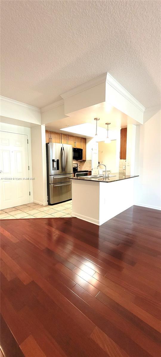 2000 N Bayshore Dr Unit 509, Miami, FL 33137 - kitchen featuring stainless steel refrigerator with ice dispenser, black microwave, light wood-type flooring, dark countertops, and crown molding
