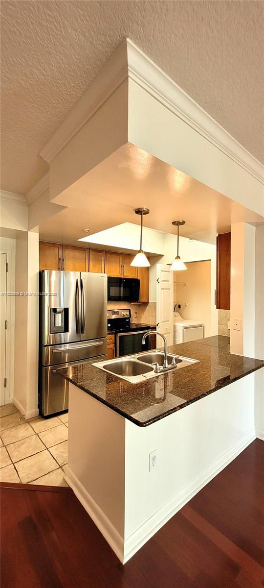 2000 N Bayshore Dr Unit 509, Miami, FL 33137 - kitchen with appliances with stainless steel finishes, independent washer and dryer, crown molding, a textured ceiling, and brown cabinetry