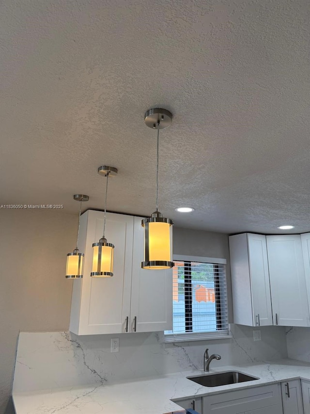 2441 NW 140th St, Opa Locka, FL 33054 - kitchen with a textured ceiling, light stone countertops, pendant lighting, white cabinets, and decorative backsplash