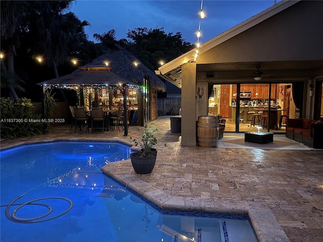 8878 SW 59th St, Cooper City, FL 33328 - pool at twilight featuring a gazebo, a patio area, a ceiling fan, and outdoor dining space