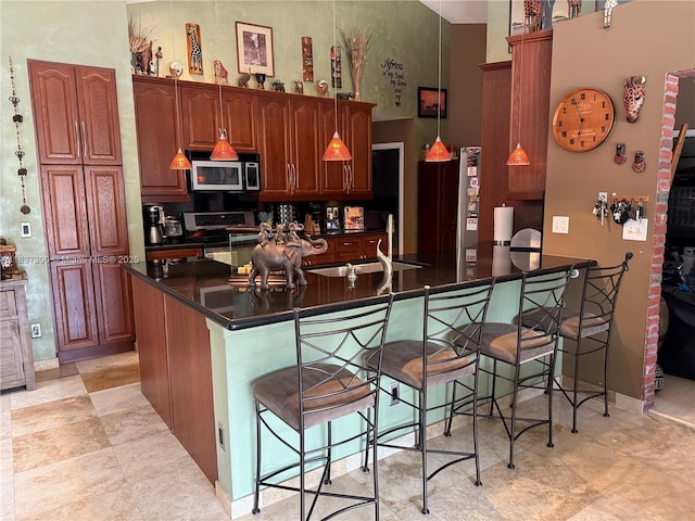 8878 SW 59th St, Cooper City, FL 33328 - kitchen featuring appliances with stainless steel finishes, dark countertops, a kitchen breakfast bar, a peninsula, and a high ceiling