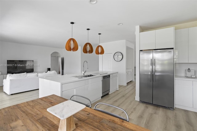 1249 Chenille Cir, Weston, FL 33327 - kitchen featuring appliances with stainless steel finishes, light wood-style floors, arched walkways, light countertops, and white cabinetry