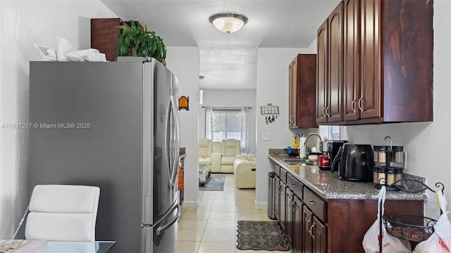 3109 NW 64th St, Miami, FL 33147 - kitchen featuring freestanding refrigerator, light tile patterned flooring, a textured ceiling, dark brown cabinets, and stone counters