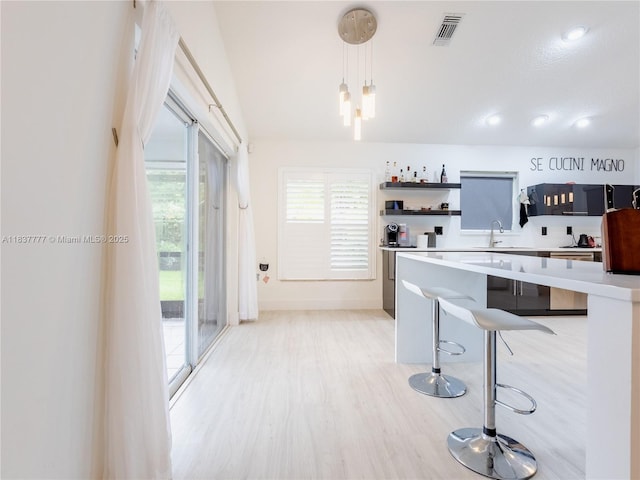 6110 Pitch Ln, Boynton Beach, FL 33437 - kitchen featuring open shelves, light countertops, light wood finished floors, a breakfast bar, and pendant lighting