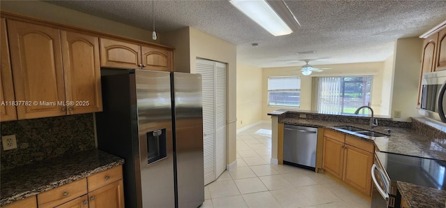 2957 Oak Park Cir, Davie, FL 33328 - kitchen featuring appliances with stainless steel finishes, brown cabinetry, dark stone counters, light tile patterned floors, and a textured ceiling