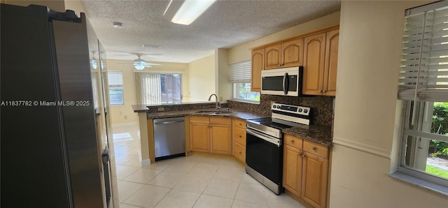 2957 Oak Park Cir, Davie, FL 33328 - kitchen with appliances with stainless steel finishes, a peninsula, a textured ceiling, light tile patterned floors, and dark stone counters
