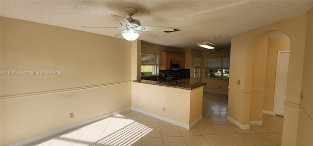 2957 Oak Park Cir, Davie, FL 33328 - kitchen with stainless steel appliances, arched walkways, light tile patterned flooring, plenty of natural light, and a textured ceiling