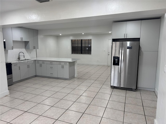 2855 SW 10th St, Fort Lauderdale, FL 33312 - kitchen featuring stainless steel appliances, light countertops, a peninsula, backsplash, and light tile patterned floors