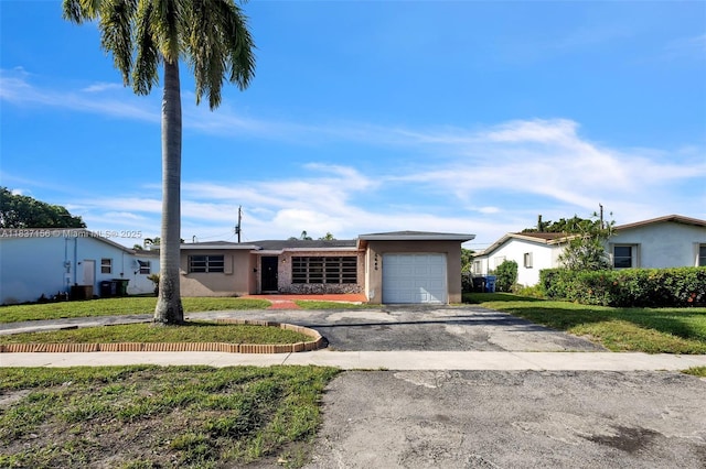 5640 NW 13th Ct, Lauderhill, FL 33313 - ranch-style house with an attached garage, asphalt driveway, stucco siding, and a front lawn