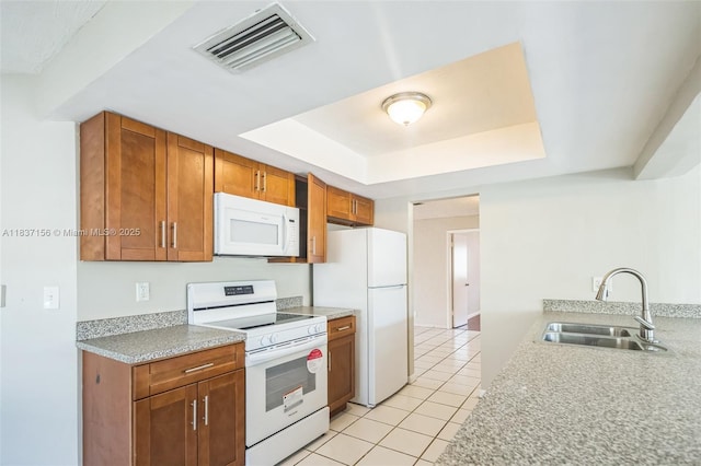 5640 NW 13th Ct, Lauderhill, FL 33313 - kitchen with white appliances, a tray ceiling, light tile patterned floors, brown cabinetry, and light countertops