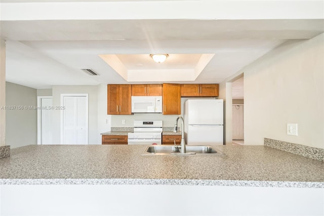 5640 NW 13th Ct, Lauderhill, FL 33313 - kitchen featuring white appliances, a tray ceiling, brown cabinets, a peninsula, and light countertops