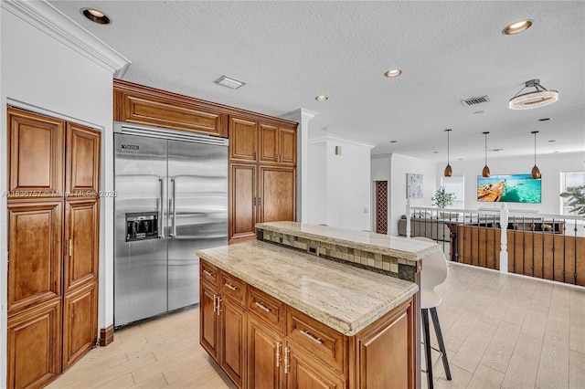 19480 SW 39th Ct, Miramar, FL 33029 - kitchen with built in refrigerator, brown cabinetry, a center island, light wood-style flooring, and a kitchen breakfast bar