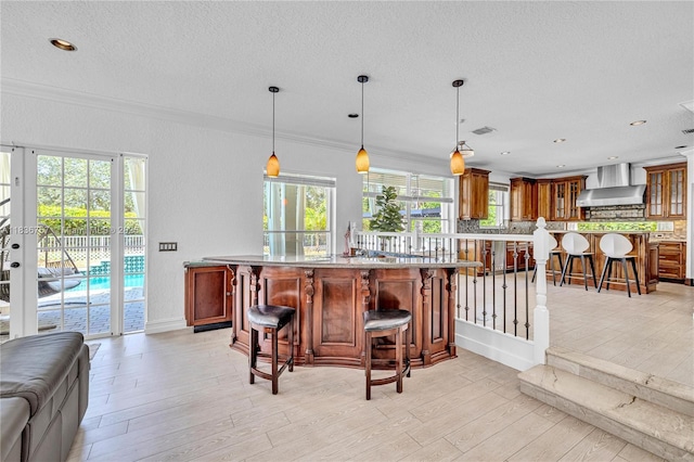 19480 SW 39th Ct, Miramar, FL 33029 - kitchen featuring wall chimney range hood, a breakfast bar area, glass insert cabinets, healthy amount of natural light, and a textured ceiling