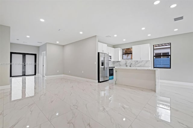 1244 NW 30th Ave, Fort Lauderdale, FL 33311 - kitchen featuring stainless steel appliances, white cabinets, light marble finish floors, open floor plan, and backsplash