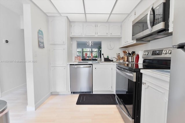 1501 S Ocean Blvd Unit 227, Lauderdale By The Sea, FL 33062 - kitchen featuring stainless steel appliances, white cabinets, light wood-style floors, light countertops, and a drop ceiling
