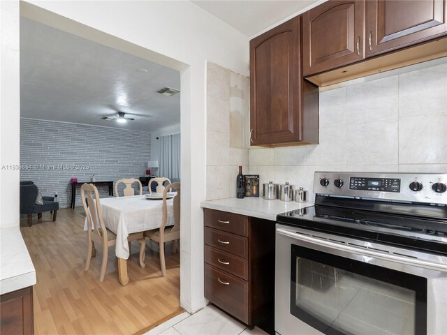 6530 Tyler St, Hollywood, FL 33024 - kitchen with stainless steel range with electric stovetop, light countertops, light wood-style flooring, tasteful backsplash, and open floor plan