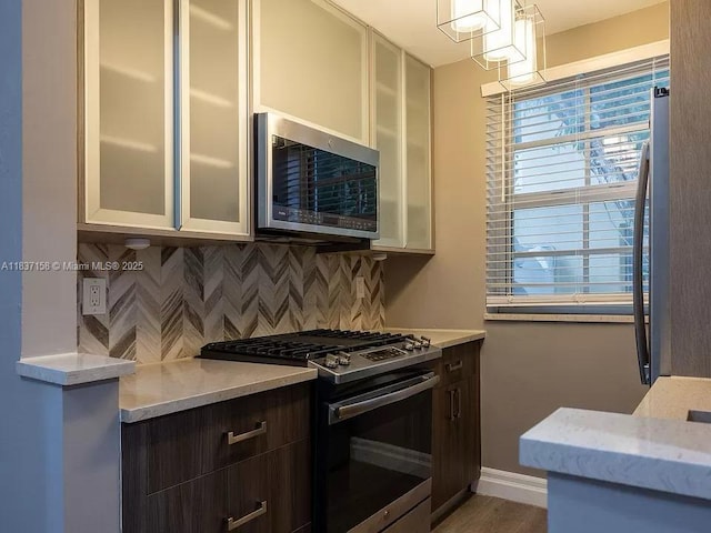1611 Euclid Ave Unit 5, Miami Beach, FL 33139 - kitchen featuring stainless steel appliances, backsplash, glass insert cabinets, light stone countertops, and white cabinets