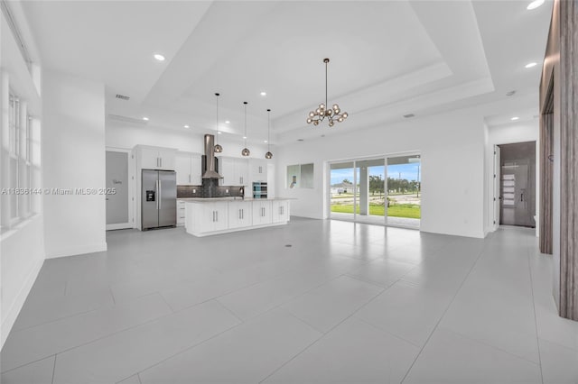 121 SW Sea Lion Rd, Port St Lucie, FL 34953 - unfurnished living room featuring a raised ceiling, recessed lighting, a chandelier, and light tile patterned floors