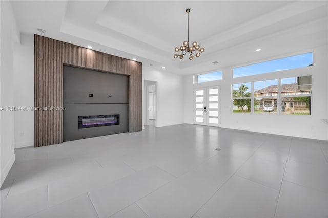 121 SW Sea Lion Rd, Port St Lucie, FL 34953 - unfurnished living room with a tray ceiling, recessed lighting, a glass covered fireplace, french doors, and a chandelier