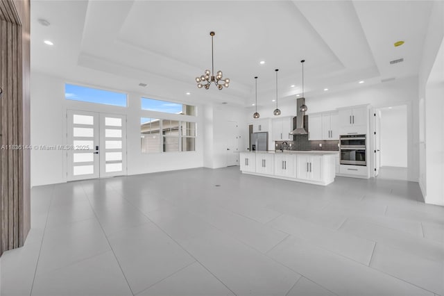 121 SW Sea Lion Rd, Port St Lucie, FL 34953 - unfurnished living room with a raised ceiling, a chandelier, french doors, recessed lighting, and light tile patterned flooring