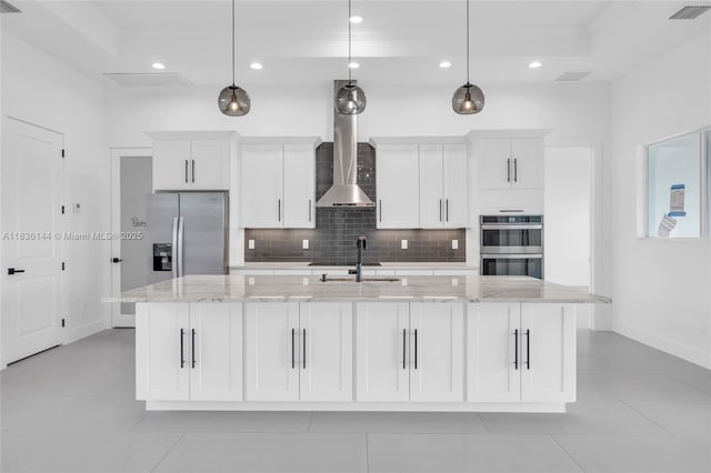 121 SW Sea Lion Rd, Port St Lucie, FL 34953 - kitchen with wall chimney exhaust hood, stainless steel appliances, a large island, tasteful backsplash, and white cabinets