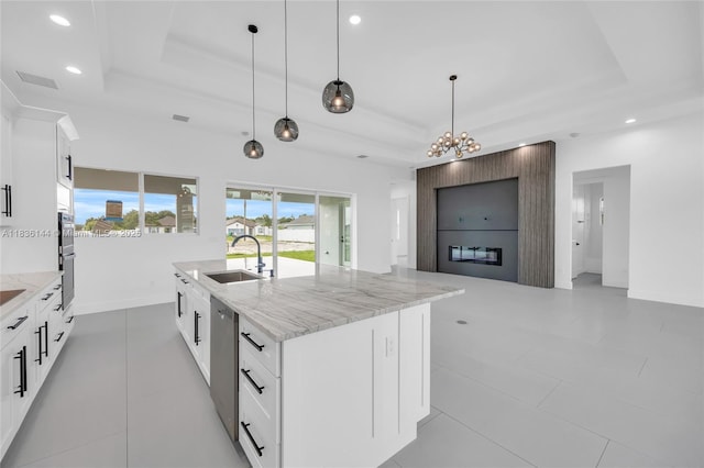 121 SW Sea Lion Rd, Port St Lucie, FL 34953 - kitchen with a raised ceiling, light stone countertops, an island with sink, recessed lighting, and white cabinets