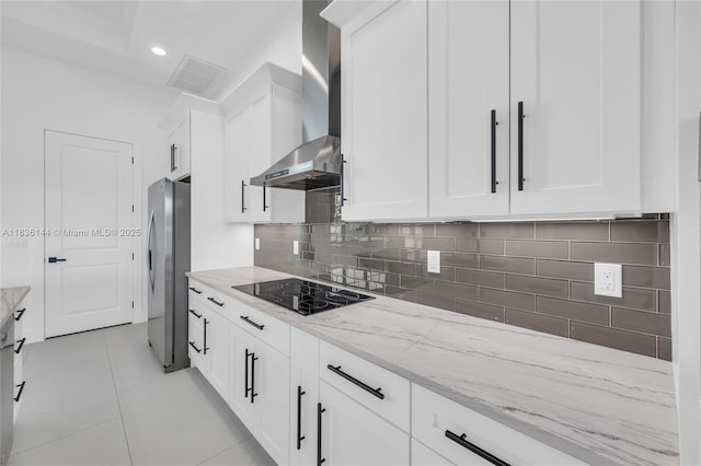 121 SW Sea Lion Rd, Port St Lucie, FL 34953 - kitchen featuring wall chimney range hood, freestanding refrigerator, black electric stovetop, light stone counters, and white cabinetry