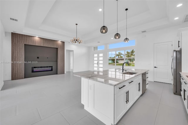 121 SW Sea Lion Rd, Port St Lucie, FL 34953 - kitchen with a raised ceiling, appliances with stainless steel finishes, light stone counters, an island with sink, and recessed lighting