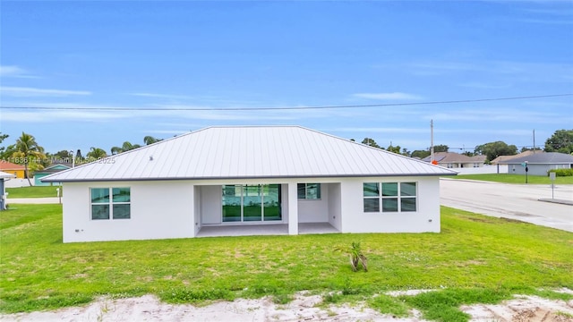 121 SW Sea Lion Rd, Port St Lucie, FL 34953 - back of house featuring stucco siding, a metal roof, a yard, and a patio