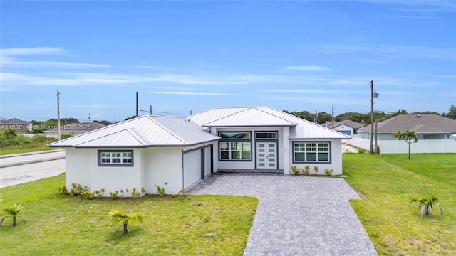 121 SW Sea Lion Rd, Port St Lucie, FL 34953 - view of front of house with french doors, an attached garage, a metal roof, a standing seam roof, and decorative driveway