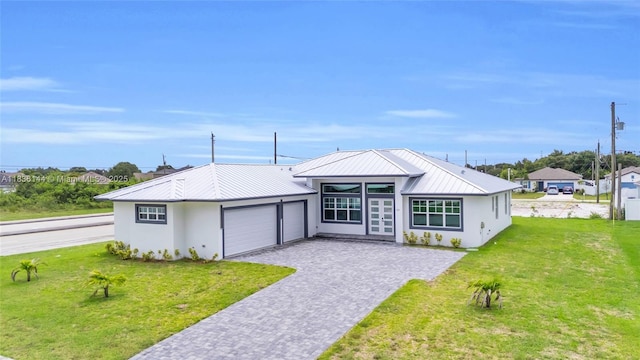 121 SW Sea Lion Rd, Port St Lucie, FL 34953 - view of front facade featuring an attached garage, decorative driveway, a metal roof, and a front yard