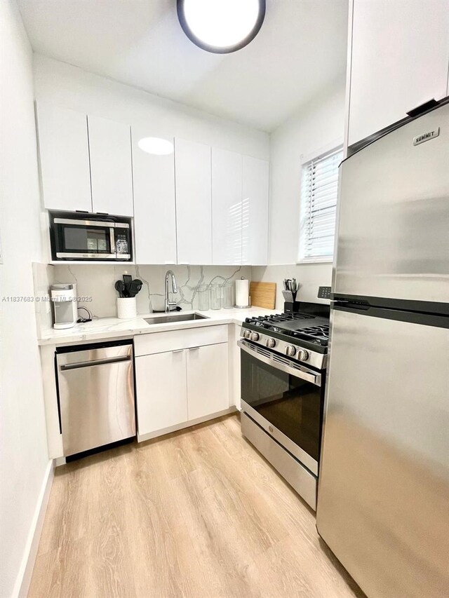 936 Pennsylvania Ave Unit 101, Miami Beach, FL 33139 - kitchen with appliances with stainless steel finishes, light wood finished floors, white cabinets, and light countertops