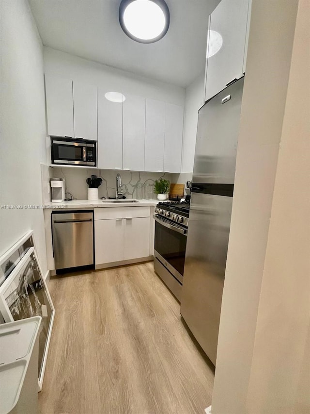 936 Pennsylvania Ave Unit 101, Miami Beach, FL 33139 - kitchen with appliances with stainless steel finishes, light wood finished floors, white cabinetry, light countertops, and modern cabinets
