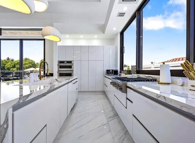 2225 NE 19th St, Fort Lauderdale, FL 33305 - kitchen with modern cabinets, white cabinetry, light marble finish floors, light stone counters, and plenty of natural light