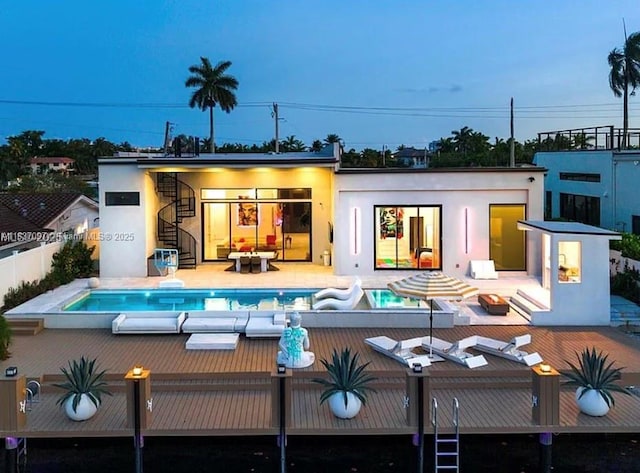 2225 NE 19th St, Fort Lauderdale, FL 33305 - back of property featuring stucco siding, a deck, stairway, and an outdoor pool