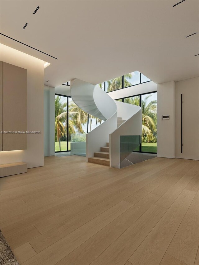 1661 Onaway Dr, Miami, FL 33133 - unfurnished living room featuring wood finished floors, a wall of windows, and stairway