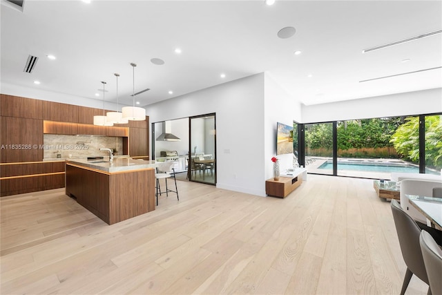 260 NW 47th St, Miami, FL 33127 - kitchen with modern cabinets, light countertops, tasteful backsplash, light wood-type flooring, and brown cabinets