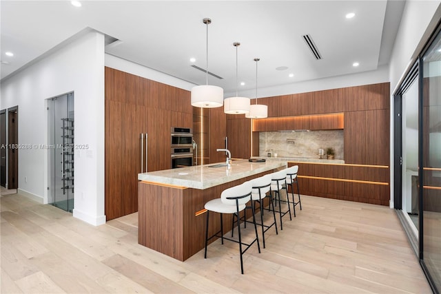 260 NW 47th St, Miami, FL 33127 - kitchen with modern cabinets, brown cabinetry, tasteful backsplash, recessed lighting, and light wood finished floors