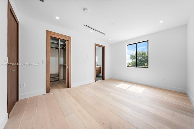 260 NW 47th St, Miami, FL 33127 - unfurnished bedroom featuring light wood-style flooring, recessed lighting, a spacious closet, and ensuite bath
